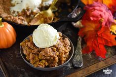 a close up of a bowl of food with ice cream on top and pumpkins in the background