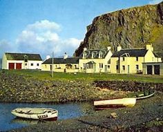 there is a small boat on the water in front of some houses and a mountain