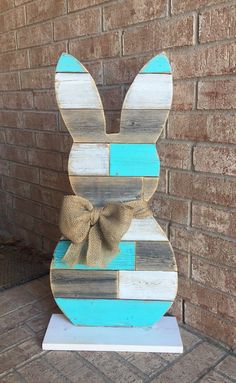 a wooden bunny with a bow on it's head sitting in front of a brick wall