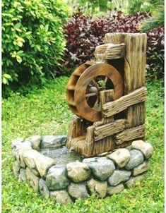 a wooden water wheel sitting on top of a lush green field