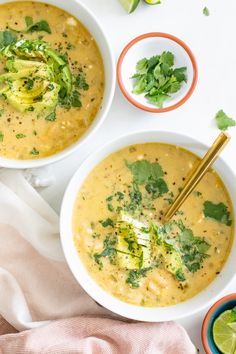 two bowls filled with soup and garnished with cilantro, broccoli and lime