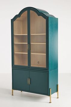 a green cabinet with glass doors and gold legs