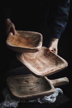 two wooden bowls stacked on top of each other, one being held over the other