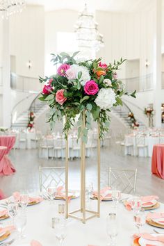 an elegant centerpiece with pink and white flowers sits on top of a round table