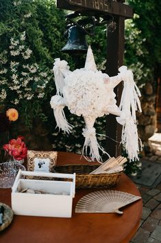 a wooden table topped with white flowers and a bell hanging from it's side