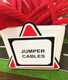 there is a sign that says jumper cables in the shape of a box with red yarn on it