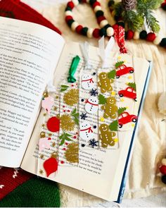 an open book sitting on top of a blanket next to christmas decorations