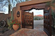 the entrance to an adobe style home with cactus and cacti