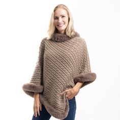 Elevate your cold-weather wardrobe with the Fur Trimmed Cozy Cable Poncho, a luxurious blend of warmth, style, and sophistication. This cable knit poncho is crafted from soft 100% polyester, offering a cozy feel while draping beautifully over your shoulders. The warm brown hue adds richness and depth, while the fancy faux fur trim along the neckline and edges brings an extra touch of elegance. Designed with the flexibility of a poncho, this piece is perfect for layering over your favorite outfit Winter Cable Knit Outerwear One Size, Cable Knit Outerwear In One Size, Winter Poncho With Faux Fur Trim, Winter Faux Fur Poncho With Trim, Cozy Winter Poncho For Cold Weather, Cozy Soft Knit Winter Poncho, Brown Knit Poncho For Winter, Brown Knit Winter Poncho, Winter Brown Knit Poncho