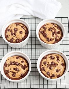 three white bowls filled with chocolate chip cookies on top of a cooling rack next to a napkin