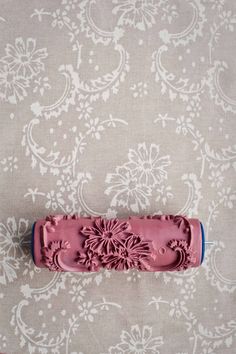 a pink object sitting on top of a table next to a wallpaper covered in white flowers