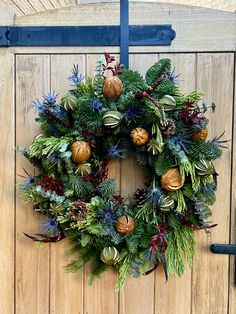 a christmas wreath hanging on a wooden door with pine cones and evergreens around it