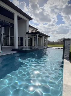 an empty swimming pool in front of a house with the sun reflecting off it's windows