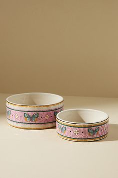 two pink bowls with butterflies on them are sitting next to each other in front of a beige wall