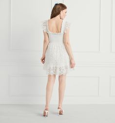 An exciting new addition to our Collector's edit, meet the Lace Elizabeth Nap Dress®. Collector’s Edition pieces are extra special versions of our signature styles, made from elevated fabrics. The Lace Elizabeth Nap Dress® has elasticated smocking, ruffled shoulders, a mini-length skirt, and pockets. It’s a shorter version of our bestselling Ellie Nap Dress®, but now in unlined white lace, making it styleable for any bridal event. Throw on, and go!The Lace Elizabeth Nap Dress® is made unlined; w Elegant Fitted Mini Dress With Smocked Back, Elegant Mini Dress With Smocked Back, Elegant Smocked Bodice Fit And Flare Dress, Elegant Fit And Flare Dress With Smocked Bodice, Elegant White Mini Dress With Smocked Back, Elegant Mini Dress With Smocked Bodice For Brunch, Feminine Evening Dresses With Smocked Back, Elegant Mini Length Smocked Dress With Ruffles, Elegant Smocked Mini Dress With Ruffles