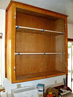 a wooden cabinet with rope hanging from it's sides and some fruit on the counter