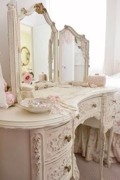 a white dresser with a mirror and pink flowers on the top shelf next to it