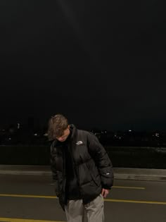 a man standing in the middle of an empty parking lot at night with his head down