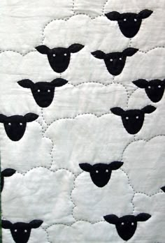 a quilted wall hanging with black sheep on it's sides and green border