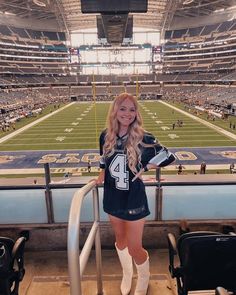 a beautiful young woman standing on top of a football field in front of an empty stadium