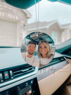 a man and woman are reflected in the mirror of a car's dash board