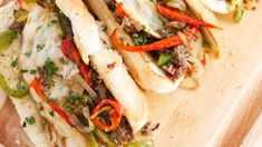 two sandwiches with meat, peppers and cheese on a cutting board