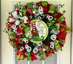 a christmas wreath on the front door with elf hats and stockings hanging from it's side