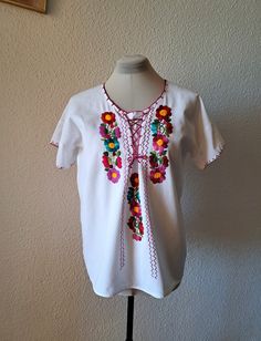 Very old women blouse with beautiful embroidered flowers and lace up at the front. Made from thick white cotton fabric. Very good vintage condition. Flat measurements: armpit to armpit  - 55 cm/21.6'' length - 65 cm/25.6'' fits like size - M/L White Cotton Peasant Top For Festival, White Cotton Festival Peasant Top, Vintage White Peasant Top For Festival, White Vintage Peasant Top For Festival, White Vintage Blouse For Festival, Folk Style Cotton Blouse With Machine Embroidery, Cotton Folk Blouse With Machine Embroidery, Vintage White Short Sleeve Peasant Top, Vintage White Peasant Top With Short Sleeves