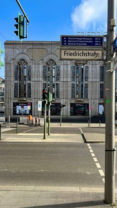 an intersection with traffic lights and street signs in front of a large building on the corner