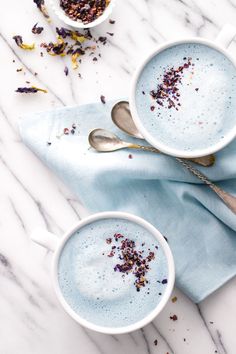 two white cups filled with blue liquid and sprinkles