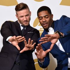 two men in suits are posing for the camera with their hands out to each other