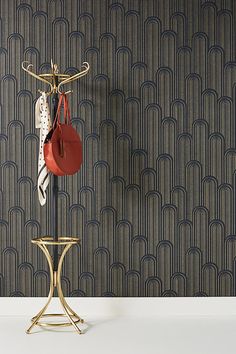 a coat rack with two purses hanging from it's hooks, in front of a wallpapered background