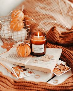 an open book with a candle on top of it next to other books and pumpkins