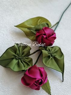 three pink and green flowers on a white surface