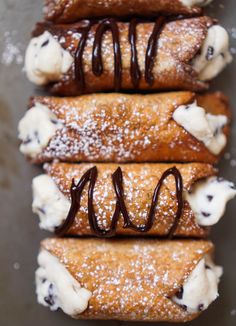 three crepes with chocolate sauce and whipped cream on top are arranged in a row