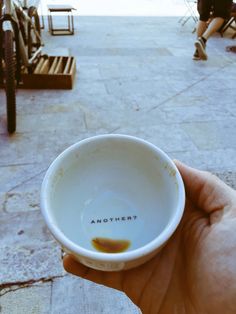 a hand holding a small white bowl with the word another written on it