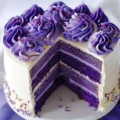 a purple cake with white frosting and sprinkles on the top slice