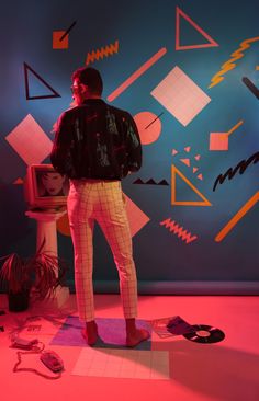 a man standing in front of a colorful wall with geometric shapes on the walls and floor