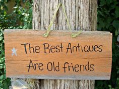 a wooden sign that says the best antiques are old friends hanging on a tree trunk