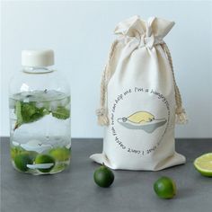 a bag with limes and water in it sitting next to a bottle filled with lemonade