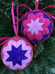 two ornaments hanging from a christmas tree decorated with pink and blue fabric, one in the shape of a flower