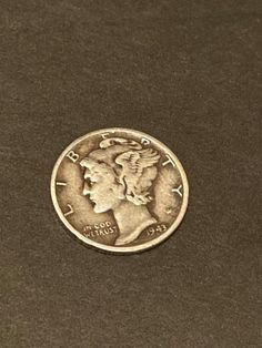 an old coin with the face of a woman's head in profile on a black surface