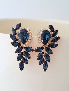 two pairs of earrings with blue stones on top of each earring, sitting on a white surface