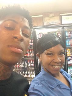 two people standing next to each other in front of shelves with drinks and sodas