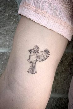 a small bird tattoo on the right side of the leg, it is black and white