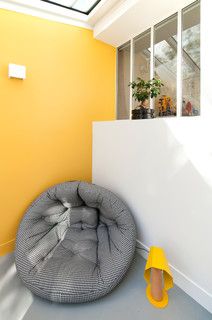 a room with yellow walls and a grey bean bag chair on the floor next to a white wall