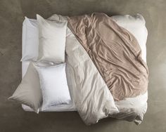 an unmade bed with several pillows and blankets on top of it, as seen from above