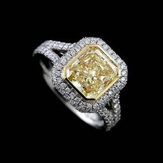 a fancy yellow diamond ring with diamonds on it's sides and the center stone surrounded by white gold