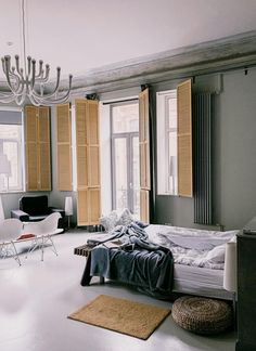 a bed sitting in the middle of a bedroom next to a window with shutters