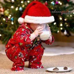 a small child wearing a santa hat drinking from a bottle